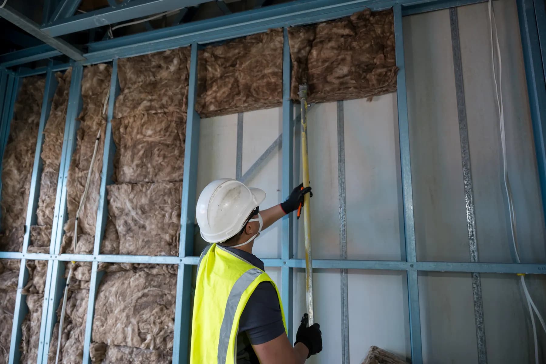 Installer placing Earthwool batts into a steel-framed wall