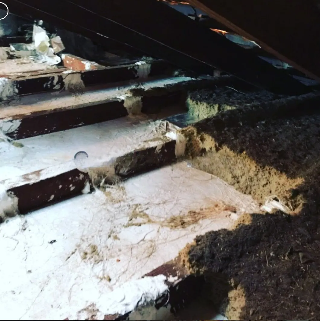 Old insulation being vacuumed out of a roof